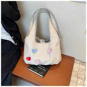 Detail der Canvas-Handtasche mit bunten Herz-Aufnähern und silberner Metallic-Kante