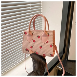 Close-up of pink corduroy crossbody bag featuring a strawberry pattern and leather handle