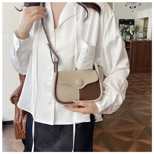 Model wearing a retro cream and coffee contrast crossbody bag with round buckle detail