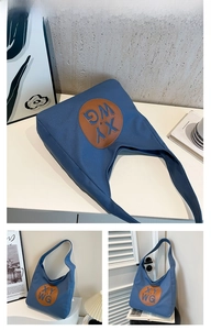 Detail of blue canvas tote bag featuring brown leather patch with XY WG lettering