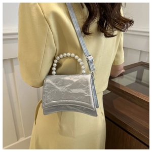 Silver hourglass bag with pearl handle shown crossbody on a model in close-up detail