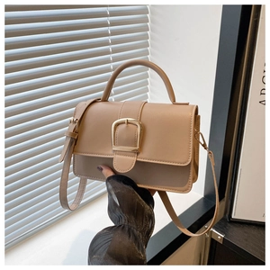 Détail du sac bandoulière beige carré avec boucle dorée et bandoulière réglable