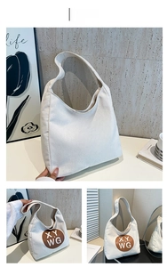 Close-up of brown leather logo patch on white canvas tote bag with XY WG print