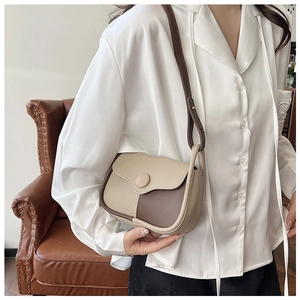 Close-up of vintage beige and brown contrast leather crossbody bag with round buckle