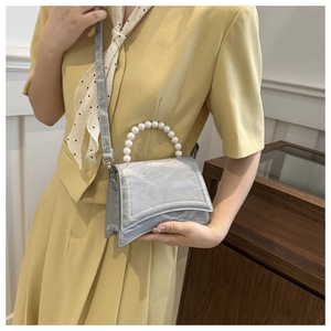 Detail of silver pleated handbag with pearl handle and shoulder strap on model