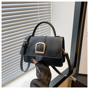 Détail du sac à main noir en similicuir avec boucle fer à cheval dorée et bandoulière