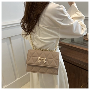 Detail of quilted leather crossbody bag with butterfly metal buckle and chain strap