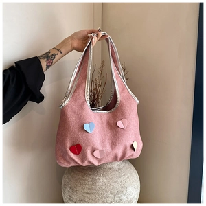 Detail der rosa Tweed-Tasche mit bunten 3D-Herz-Patches und silberner Verzierung