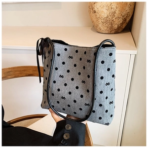 Dettaglio della borsa a secchiello in tela grigia a pois con elegante fiocco di nastro