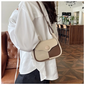 Retro two-tone saddle bag worn by a model in a vintage interior setting