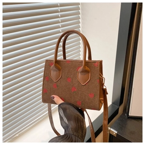 Macro detail of brown corduroy fabric with strawberry print and leather handle texture
