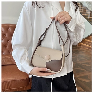 Detail of a vintage-style beige and brown crossbody bag worn by a model in a cozy room