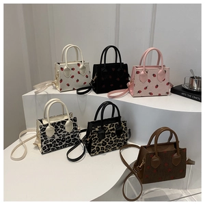 Detail of mini corduroy tote bags with strawberry and leopard prints and gold hardware