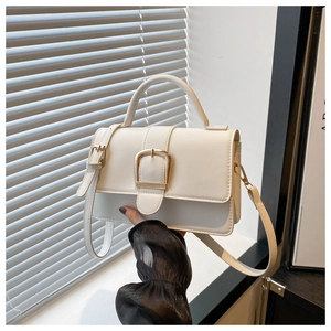 Gros plan d'un sac carré blanc avec une boucle métallique dorée sur le rabat