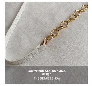 Close-up of white croc-embossed leather strap and golden chain link of a shoulder bag
