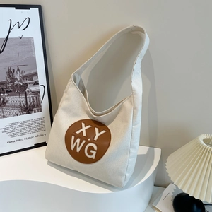 Minimalist white canvas tote bag with brown embossed leather logo patch and long shoulder strap