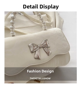 Close-up of white leather handbag featuring a silver bow and elegant pearl handle detail