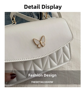Detail of white PU leather bag with geometric quilting and gold butterfly ornament