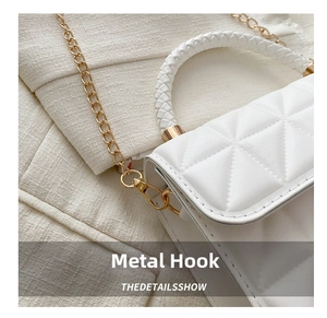 Detail of white quilted crossbody bag showing gold metal hook and woven strap texture