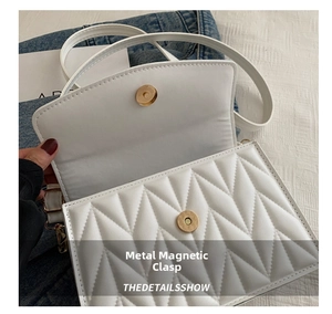 Detail showing the white quilted texture and gold magnetic buckle closure of the handbag