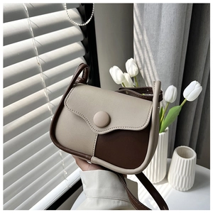 Detail of color-block saddle bag with contrast stitching and leather strap in sunlight