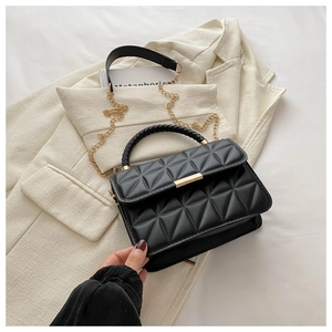 Detail of black quilted shoulder bag with gold chain strap and woven leather handle