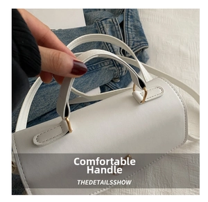 Detail of white cylinder handbag with golden butterfly clasp and comfortable handle