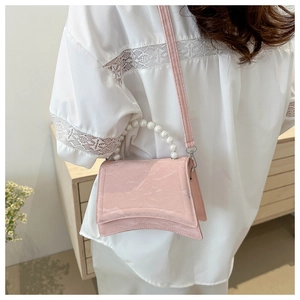 Detail of pink hourglass shoulder bag featuring pearl handle and curved bottom design