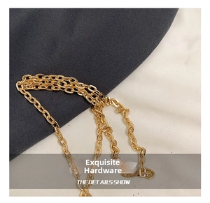 Detail shot of the polished gold metal chain strap featuring smooth oval links