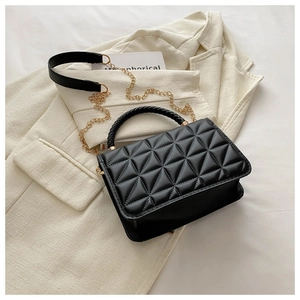 Close-up of black quilted crossbody bag with woven handle and gold chain shoulder strap
