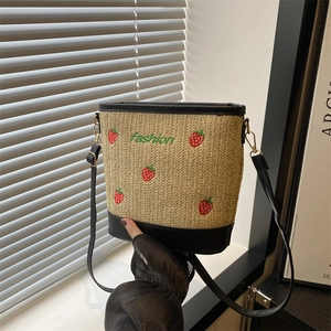 Handwoven strawberry bucket bag with black leather trim and adjustable shoulder strap