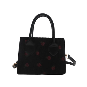 Black corduroy handbag with red strawberry prints and adjustable leather strap