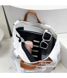 Interior view showing the large storage capacity of the white canvas tote bag with brown straps