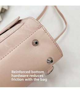Detail of light pink handbag base with protective silver metal studs and leather texture