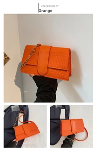 Detail view of orange crossbody bag with geometric triangle texture and gold chain strap