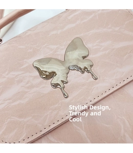 Close-up of pink textured leather bag with silver metallic butterfly and fine stitching