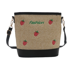 Straw bucket bag with strawberry embroidery and black leather trim on white background
