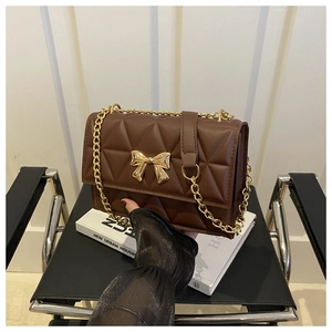 Close-up of brown quilted leather bag featuring a gold butterfly buckle and chain strap