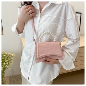 Pink pleated crossbody bag with pearl handle shown on a white shirt in a clean setting