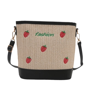Straw bucket bag with embroidered strawberries, black leather trim and adjustable strap
