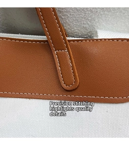 Detail of precise white stitching on premium brown leather trim of a canvas tote bag