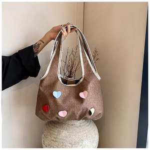 Detail einer braunen Canvas-Tasche mit bunten Herz-Patches und Silberrand