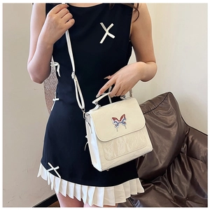 Close-up of white crossbody bag with glossy wavy texture and colorful butterfly detail