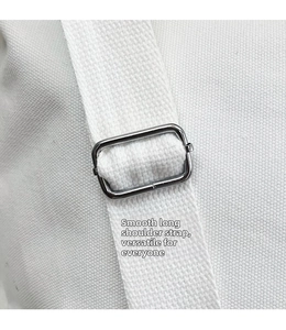 Detail of adjustable white canvas shoulder strap with silver metal buckle on tote bag