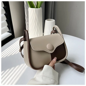 Detail of vintage beige and brown saddle bag with round buckle and adjustable strap