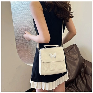 Close-up of white crinkled patent leather bag with silver butterfly buckle detail