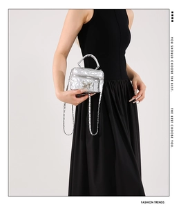 Detail of silver quilted mini box bag with hollow butterfly charm and metal chain strap