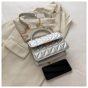 Macro detail of silver quilted bag with gold lock and metallic woven handle