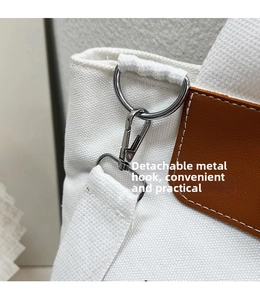 Detail of silver metal hook and detachable strap on white canvas tote bag