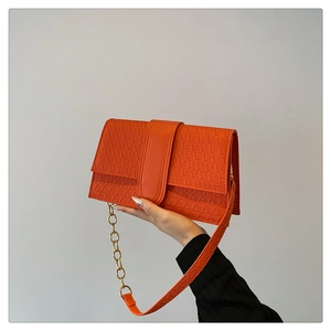 Detail of orange handbag showing geometric triangle embossing and gold chain strap